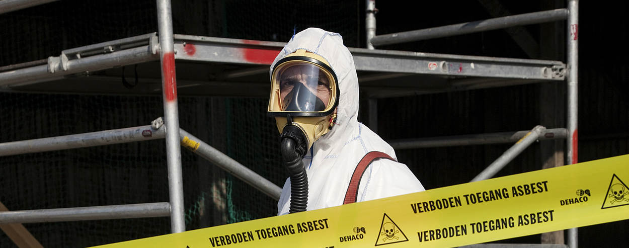 Man met beschermende kleding op een asbestverwijderingslocatie
