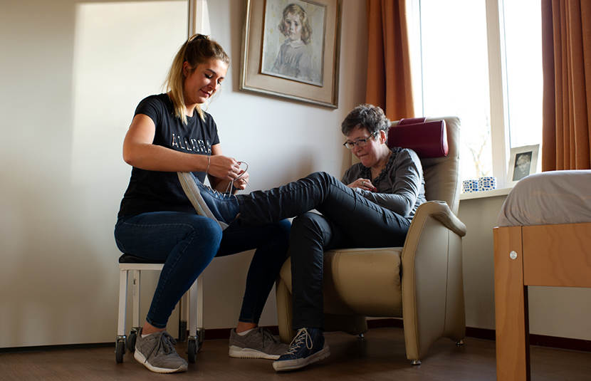 verzorgster strikt veter van een cliƫnt beide zittend op een stoel
